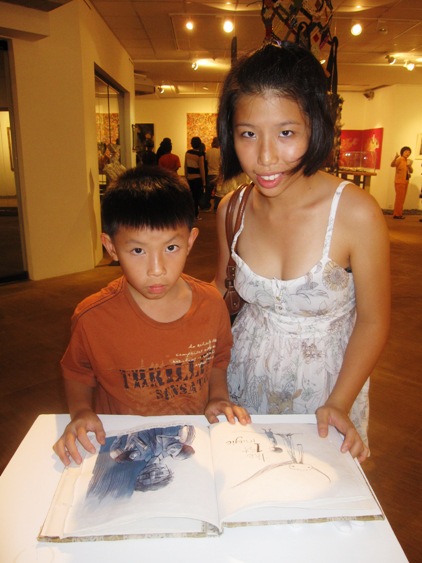 Alexander Wong and sister Wong May Kwan going through Meme’s Untitled aka Tanah Air like a story book. 